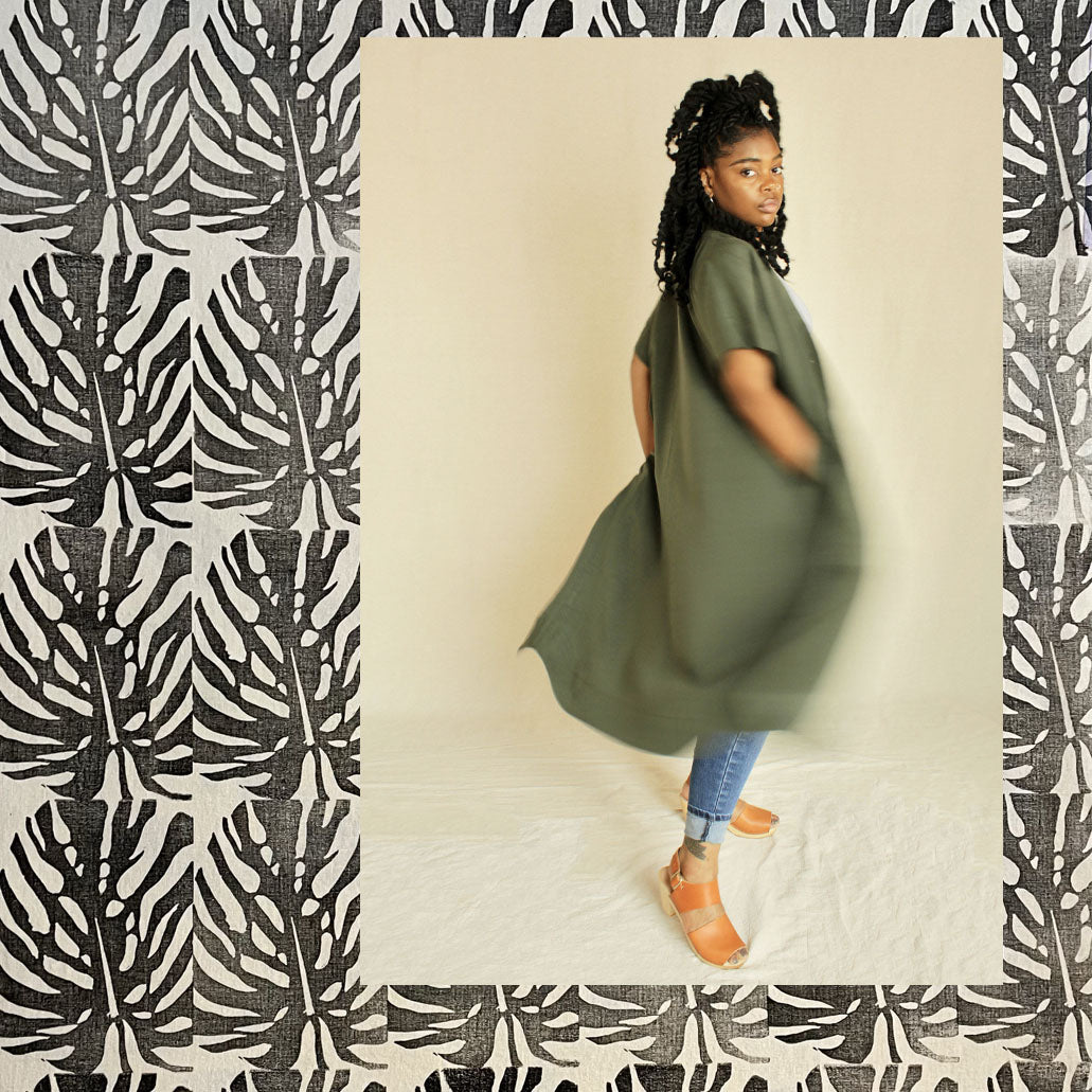 Woman wearing Sage Green duster over block printed leafy fabric.